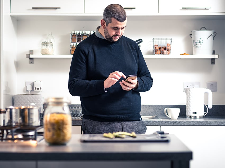 man using mobile phone in kitchen
