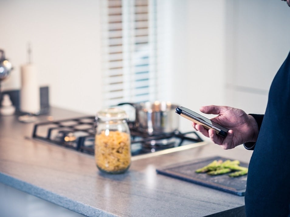 person holding mobile phone in kitchen