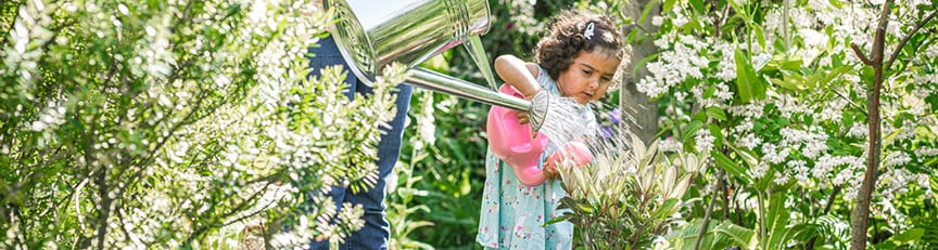 girl watering plants with watering can