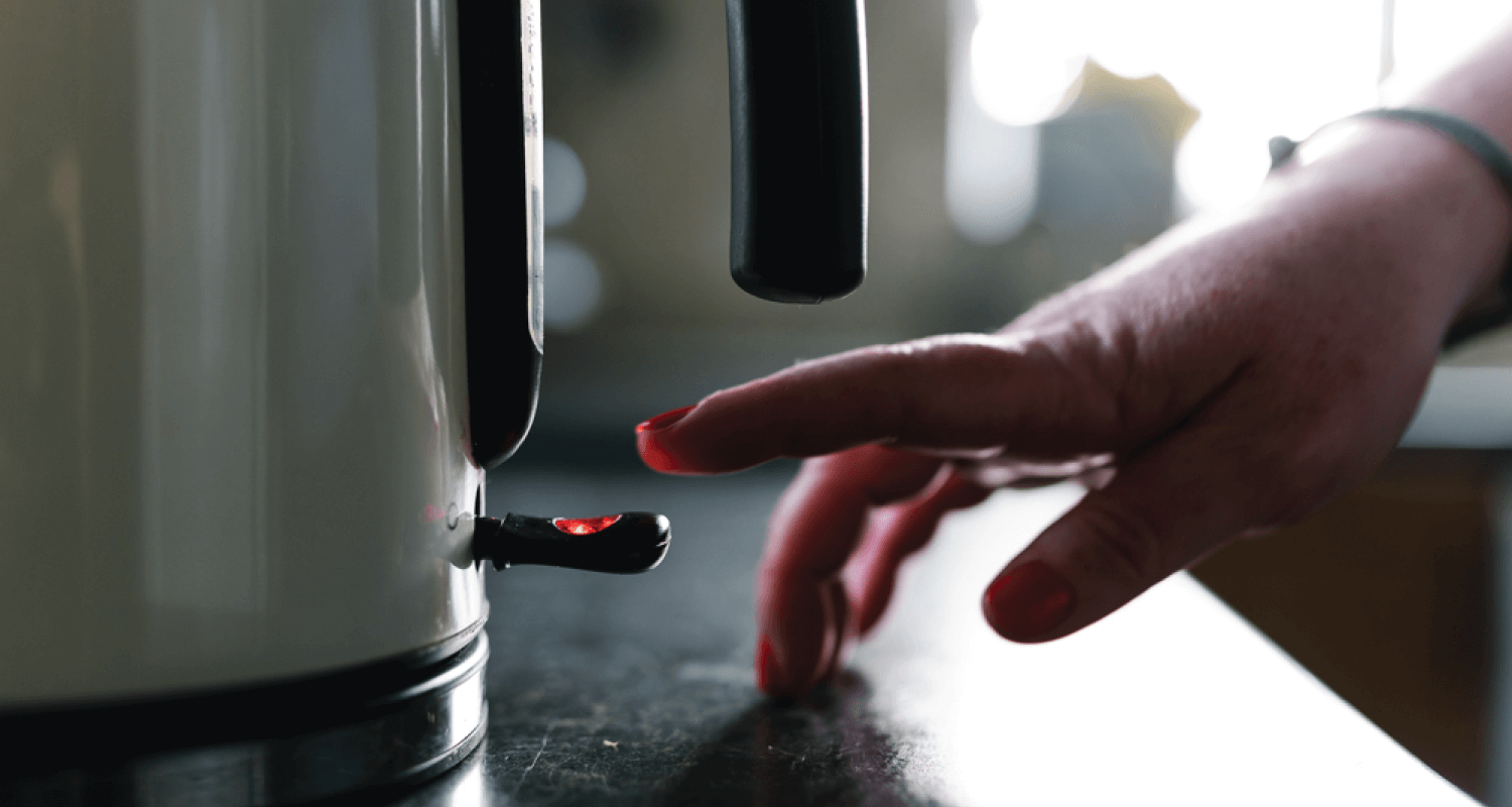 Person switching on a kettle in kitchen