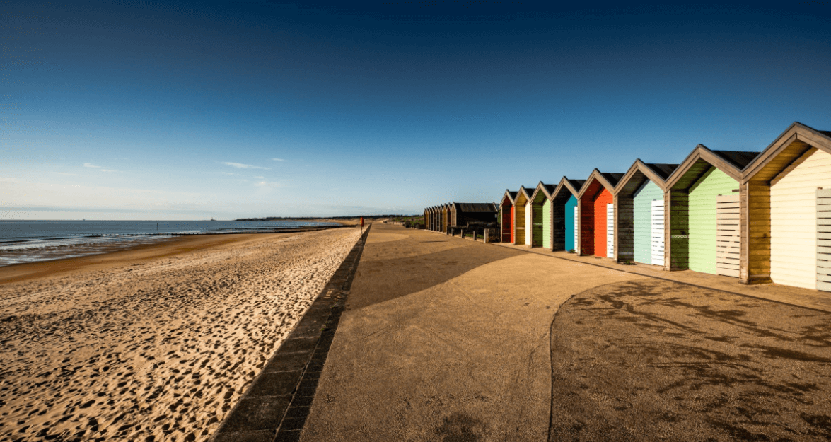Coloured beach huts next to path and beach and sea