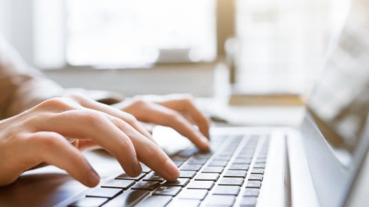 fingers typing on a laptop
