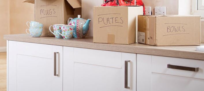 Moving home boxes and teapot and cups on kitchen bench
