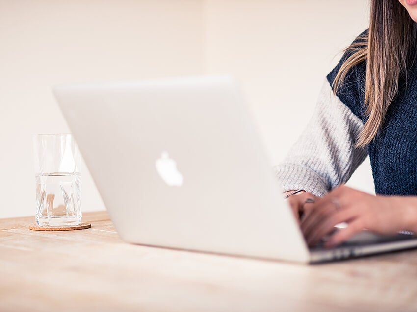 Woman on laptop with a glass of water on table