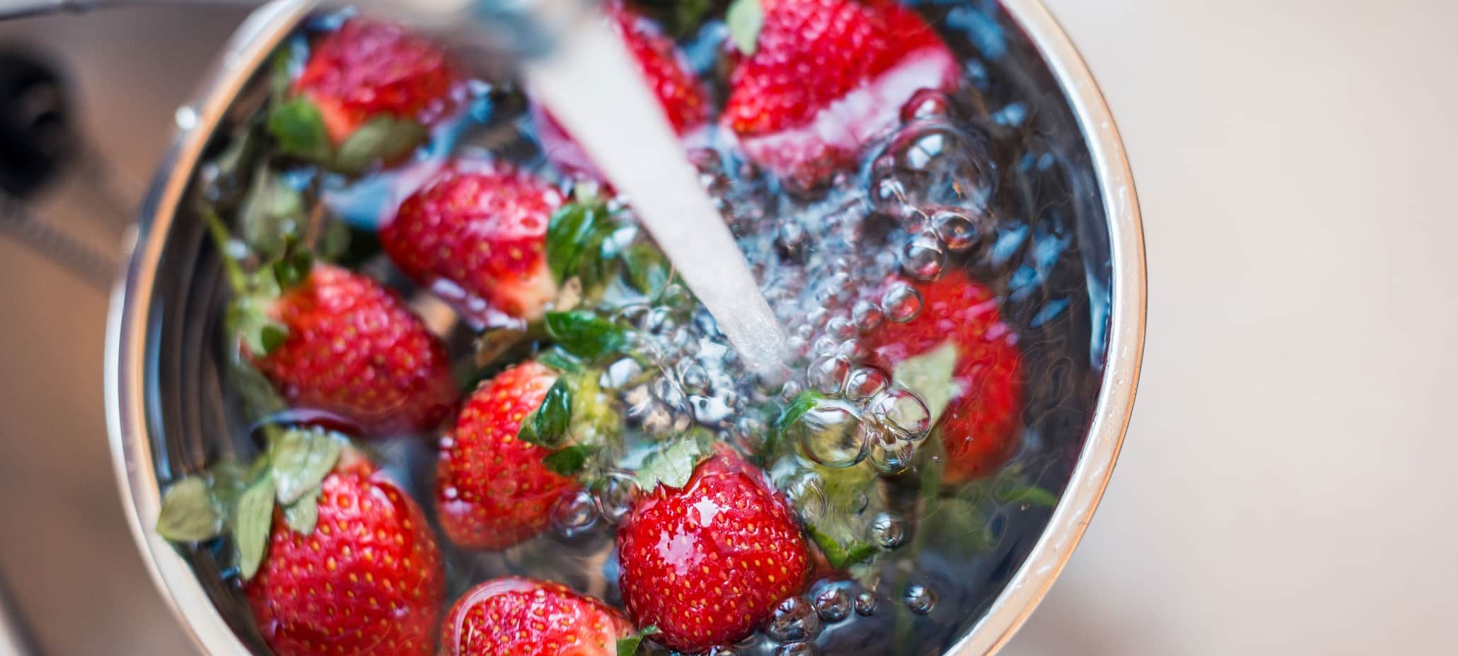 Washing strawberries under a running tap